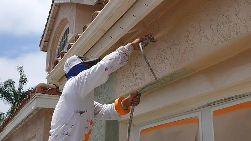 a residential house with workers painting the exterior walls